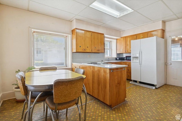 205 S Main St, Manti, UT 84642 - kitchen featuring white fridge with ice dispenser, a peninsula, healthy amount of natural light, brown cabinetry, and a paneled ceiling