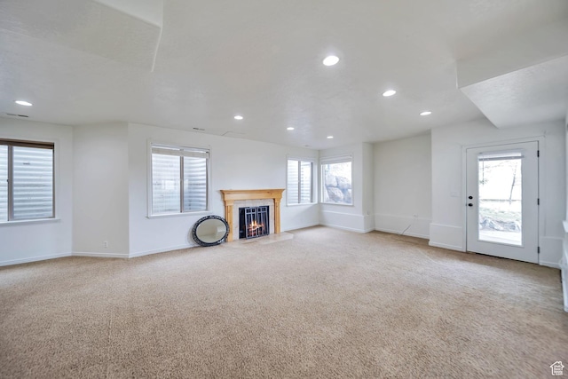 unfurnished living room featuring light colored carpet, baseboards, a lit fireplace, and recessed lighting