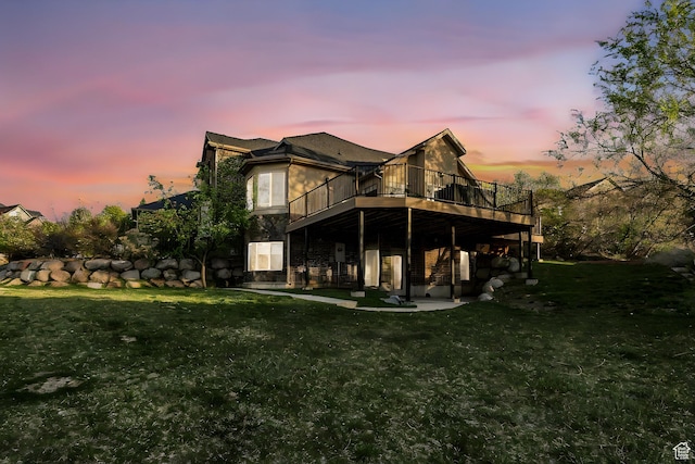 rear view of property with a wooden deck, a lawn, and a patio