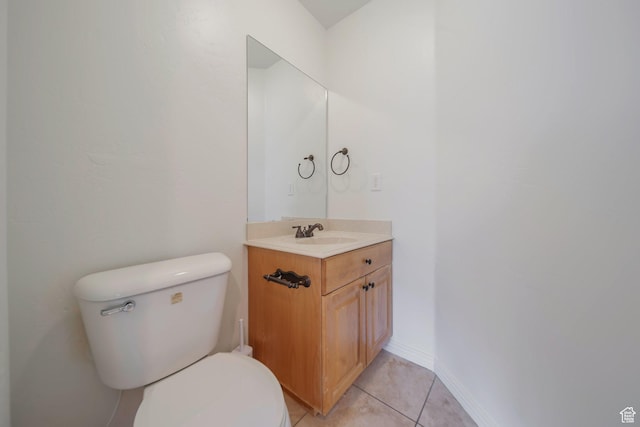 bathroom featuring baseboards, vanity, tile patterned flooring, and toilet