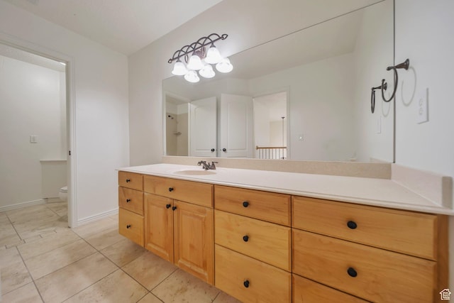 bathroom with toilet, vanity, tile patterned floors, and baseboards