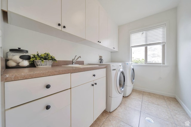 laundry room with a sink, baseboards, independent washer and dryer, cabinet space, and light tile patterned floors