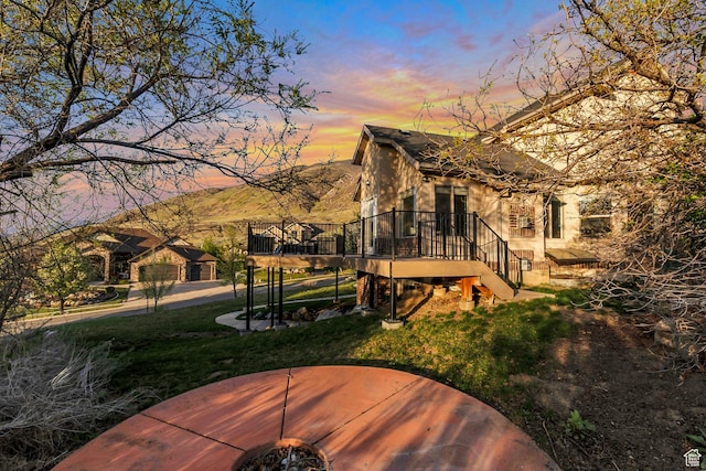 back of property featuring a fire pit, a lawn, stairway, and a deck