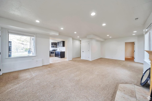 unfurnished living room with baseboards, light carpet, and recessed lighting