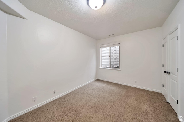 unfurnished room with baseboards, carpet, and a textured ceiling