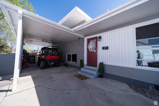 entrance to property featuring an attached carport and concrete driveway
