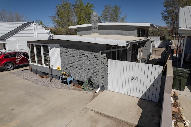 view of side of home featuring a chimney, fence, and a gate