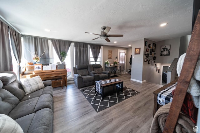living area with a textured ceiling, a ceiling fan, recessed lighting, wood finished floors, and baseboards