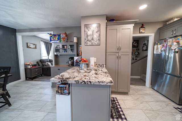 kitchen with gray cabinets, a peninsula, and freestanding refrigerator