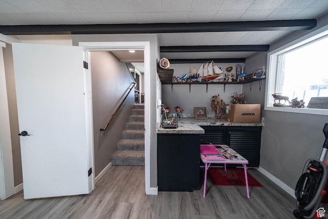 interior space featuring stairway, light wood-style flooring, baseboards, and indoor bar