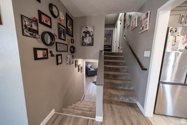 staircase featuring wood finished floors and baseboards