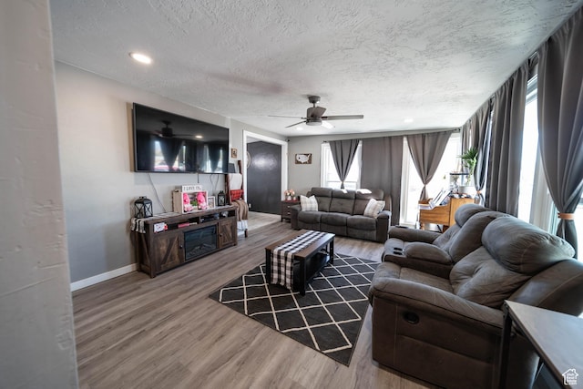 living room featuring ceiling fan, a textured ceiling, wood finished floors, and baseboards