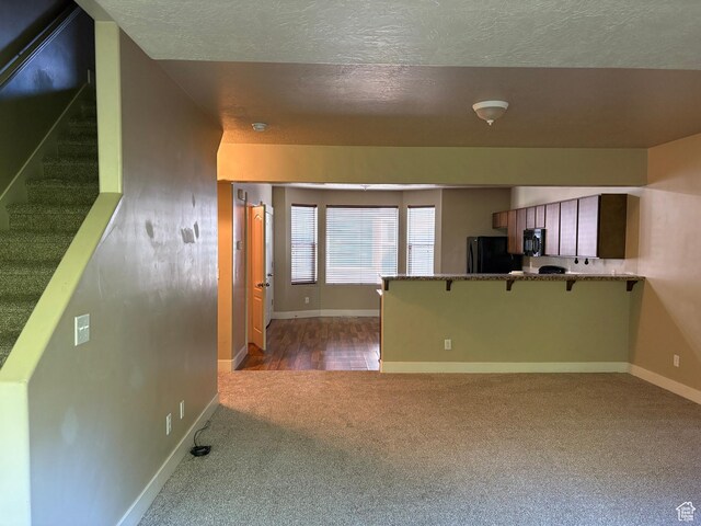 162 W Barry Links Way S, South Salt Lake, UT 84115 - interior space with black appliances, carpet flooring, baseboards, a textured ceiling, and a peninsula