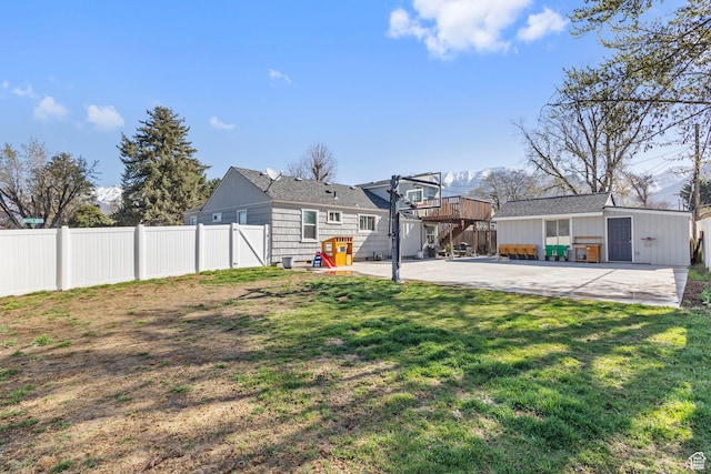 view of yard featuring a patio, a fenced backyard, and an outdoor structure