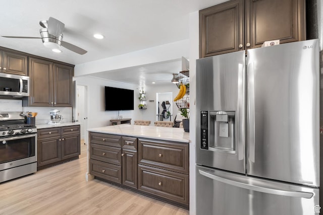 kitchen featuring appliances with stainless steel finishes, dark brown cabinetry, recessed lighting, light wood-style flooring, and light stone counters