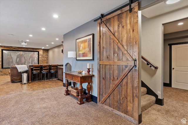hallway with carpet flooring, baseboards, recessed lighting, and a barn door