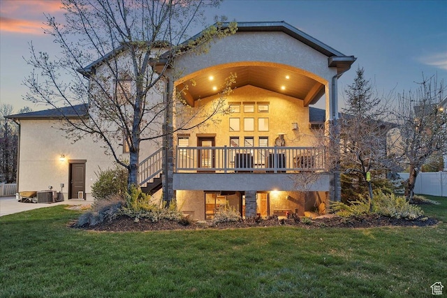 rear view of property with stucco siding, fence, and a lawn