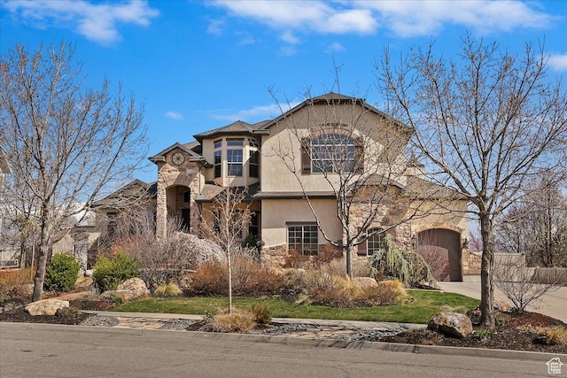 tudor-style house featuring an attached garage, stone siding, driveway, and stucco siding