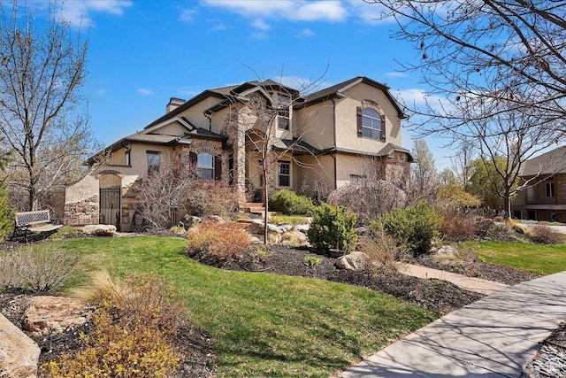 view of front of home featuring stucco siding, stone siding, and a front lawn