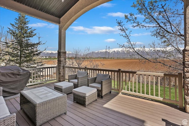 wooden terrace featuring outdoor lounge area, a rural view, a mountain view, and a grill