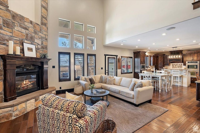 living room with recessed lighting, a fireplace, dark wood-style floors, and a high ceiling