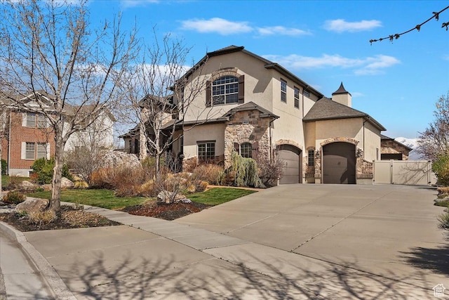 view of front facade with a garage, stucco siding, stone siding, a gate, and concrete driveway