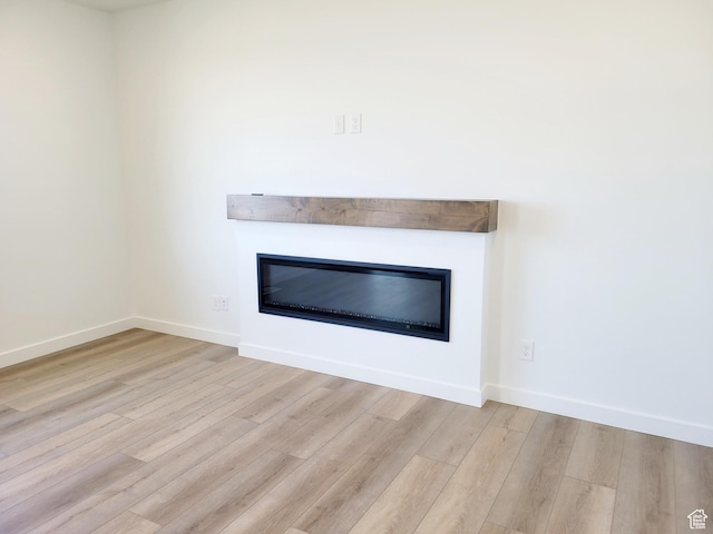 room details featuring baseboards, a glass covered fireplace, and wood finished floors