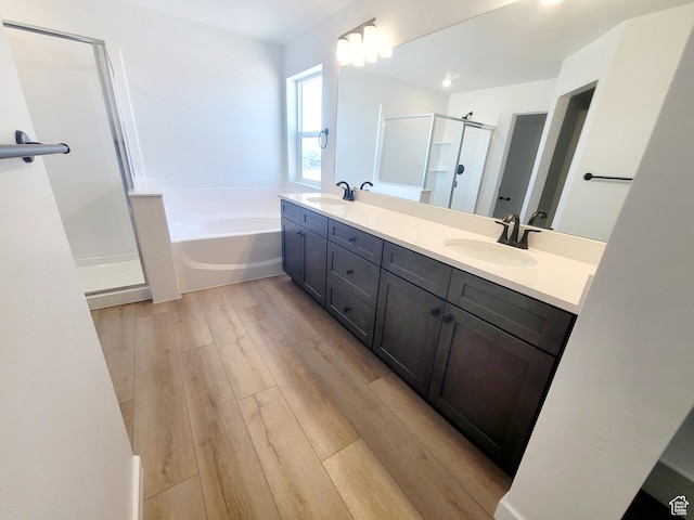 full bath featuring double vanity, a sink, a garden tub, and a stall shower