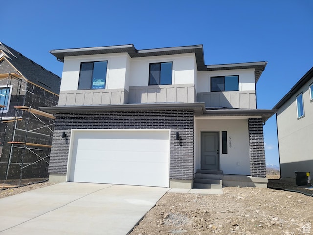 contemporary house with central air condition unit, a garage, concrete driveway, and brick siding