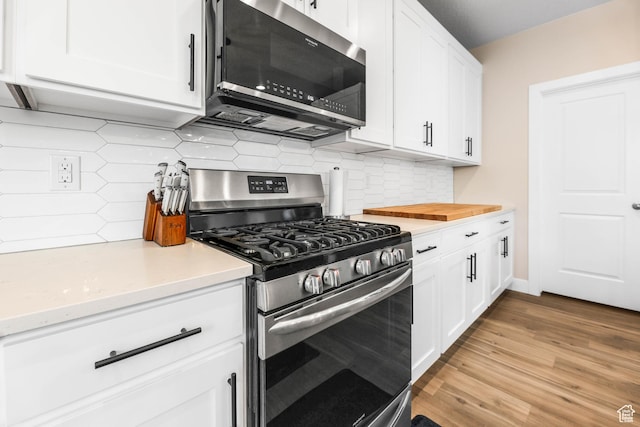 kitchen featuring white cabinets, light countertops, wood finished floors, and appliances with stainless steel finishes