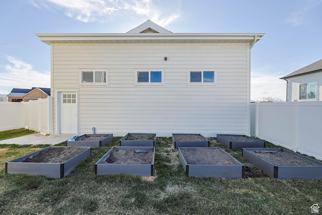 rear view of property featuring a garden and fence