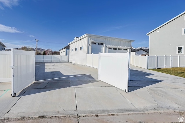 view of side of property featuring a patio, board and batten siding, a fenced backyard, and an outdoor structure
