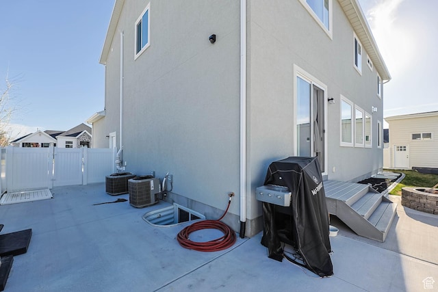 back of house with fence, cooling unit, a patio, and stucco siding