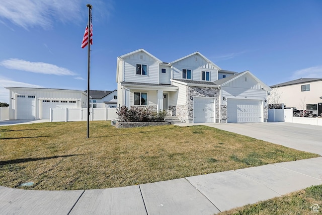 traditional home with board and batten siding, a front yard, fence, stone siding, and driveway