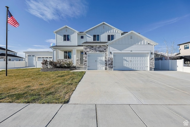 view of front facade with a front yard, stone siding, board and batten siding, fence, and concrete driveway