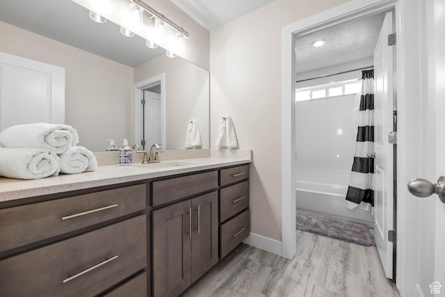 full bathroom with shower / bath combo, wood finished floors, vanity, and baseboards