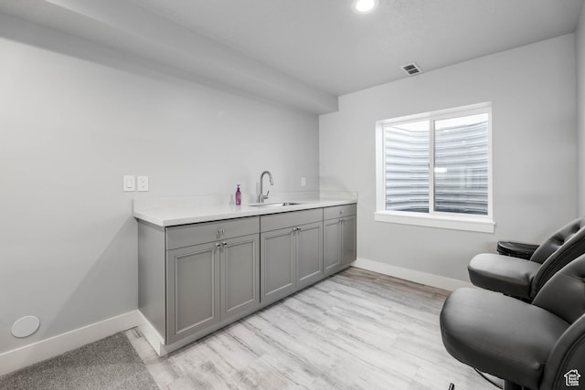 bar featuring visible vents, baseboards, a sink, light wood finished floors, and recessed lighting