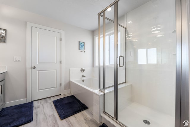 full bath featuring vanity, a bath, a stall shower, and wood finished floors