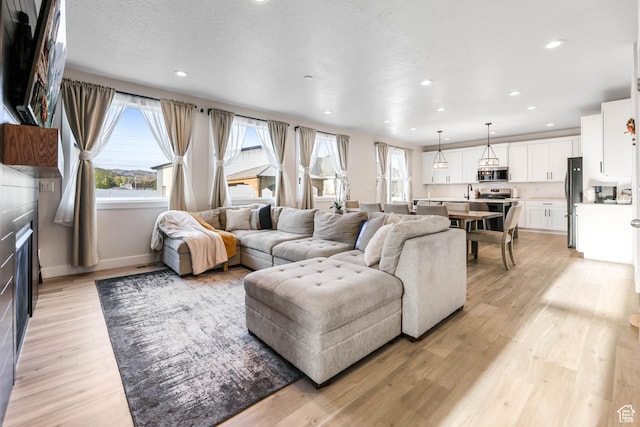 living room with baseboards, recessed lighting, and light wood-style floors