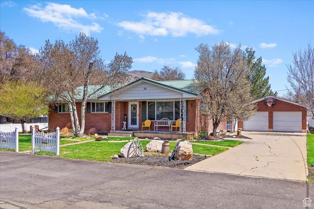 view of front facade featuring a front yard, a detached garage, a porch, fence, and brick siding