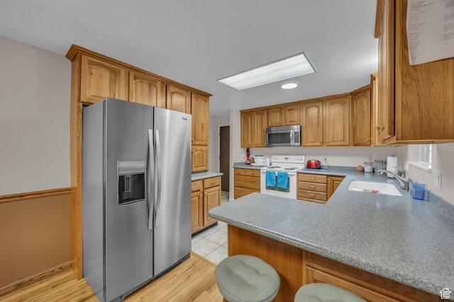 4926 S 3655 W, Taylorsville, UT 84129 - kitchen with brown cabinetry, a peninsula, light wood-type flooring, a sink, and stainless steel appliances