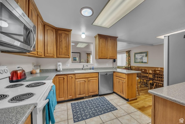 4926 S 3655 W, Taylorsville, UT 84129 - kitchen with light tile patterned floors, a sink, a peninsula, brown cabinets, and stainless steel appliances