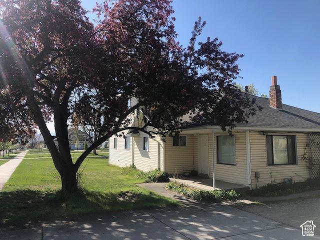 view of front of property with roof with shingles, a chimney, and a front lawn