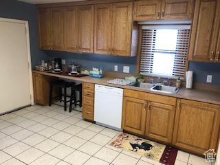 kitchen featuring a sink, brown cabinetry, built in desk, and dishwasher