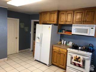 kitchen with light tile patterned floors, brown cabinetry, open shelves, and white appliances