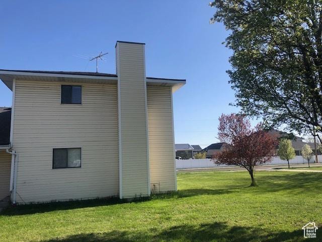 view of side of property with a chimney and a lawn