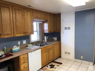 kitchen featuring brown cabinetry, dishwasher, a sink, and visible vents