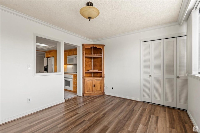 interior space featuring baseboards, a textured ceiling, ornamental molding, and wood finished floors