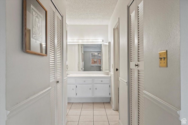 hall featuring a textured ceiling and light tile patterned floors