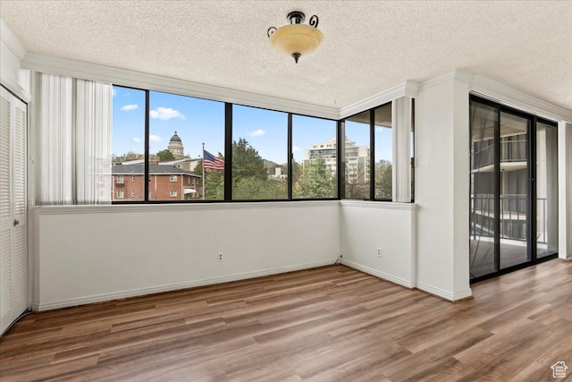 unfurnished bedroom featuring access to outside, wood finished floors, multiple windows, and a textured ceiling